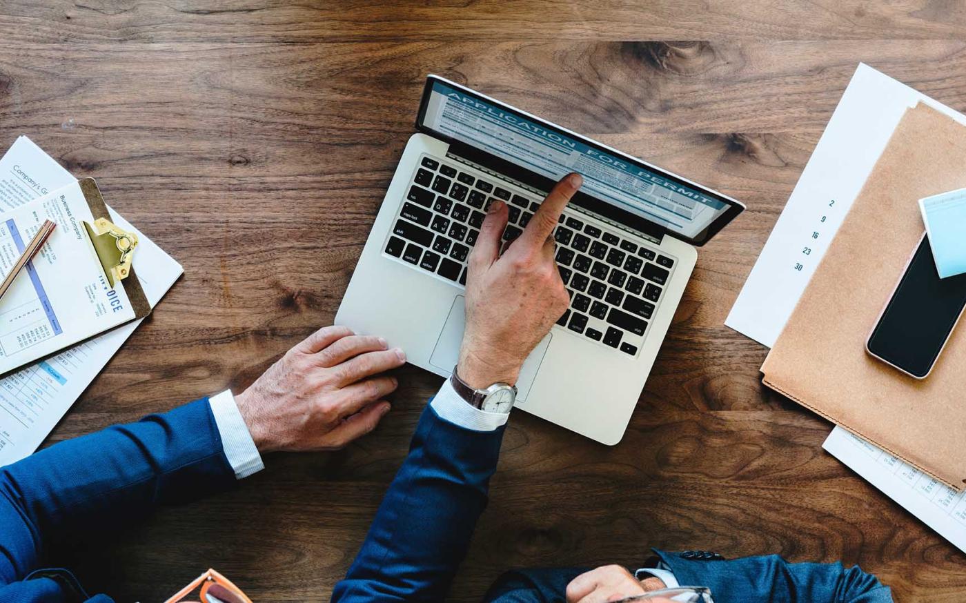 Business person pointing at laptop screen.