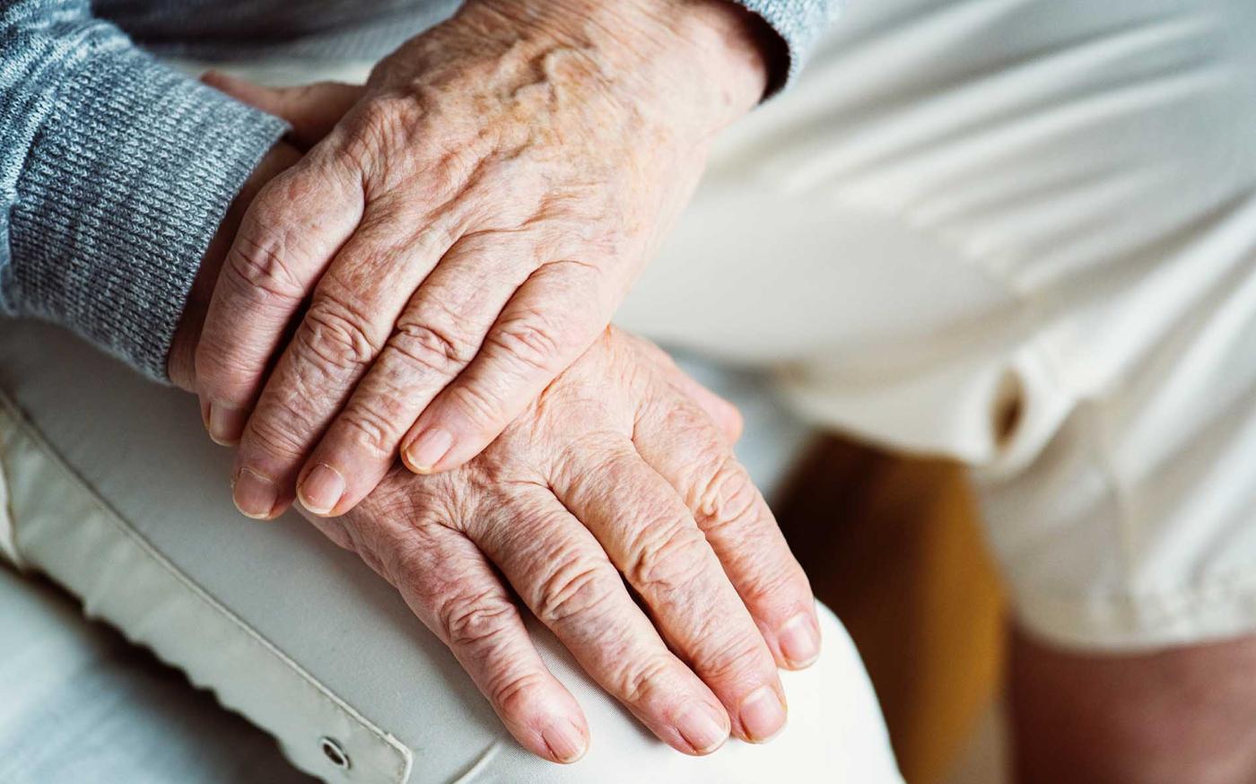 Close up of a retired couple holding hands.